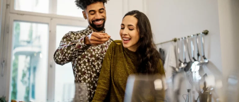 hombre dando de comer sopa de calabaza a su novia en la cocina