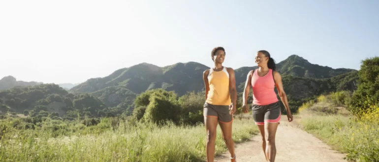 Mulheres atléticas caminhando juntas em trilhos remotos